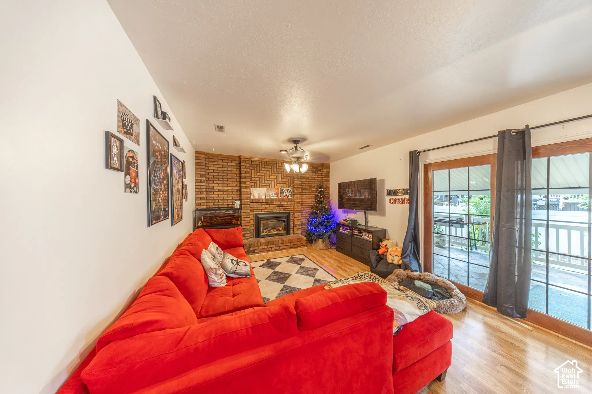Living area featuring a brick fireplace surround with an insert, hardwood flooring, and a checkered tile hearth