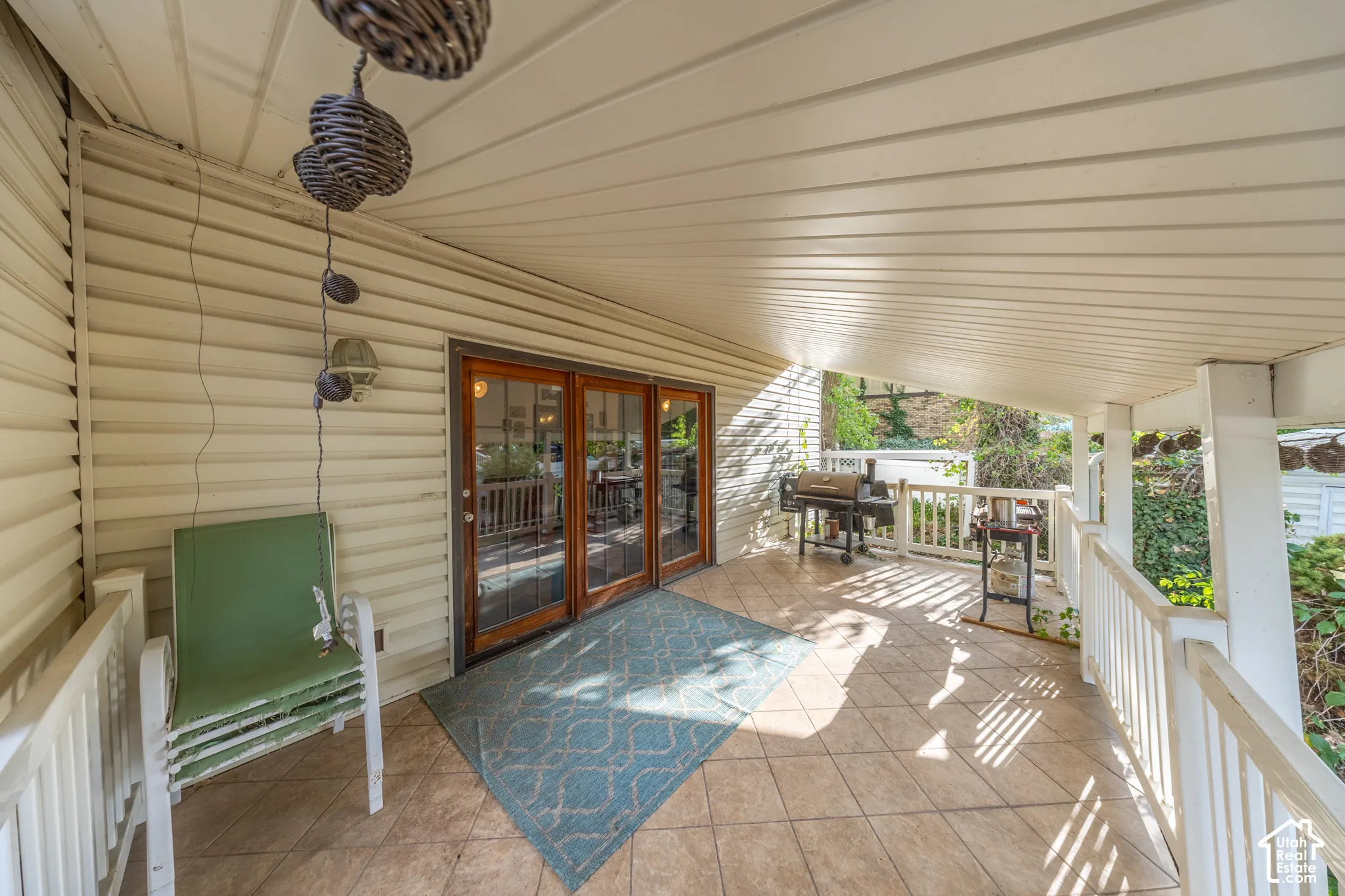 Covered porch featuring a tiled floor, white railing, and wood-framed glass patio doors