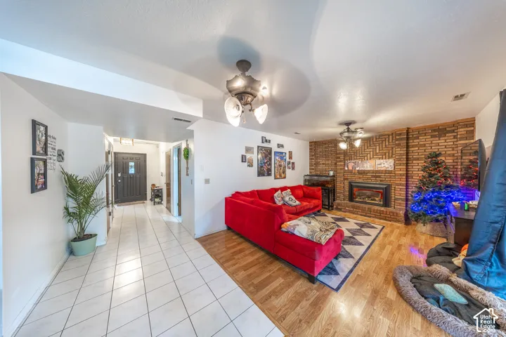 Open concept living area featuring a brick accent wall with an integrated fireplace and wood-finish flooring