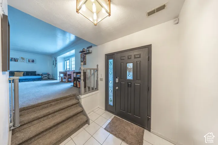 Entryway featuring a dark paneled door with decorative glass inserts, white tiled flooring, and an overhead light fixture