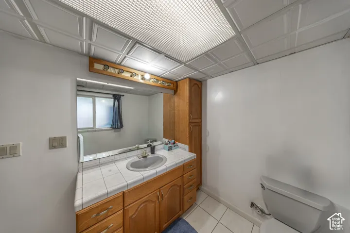 Bathroom vanity featuring wood-finish cabinetry, tile countertop, and a single basin sink