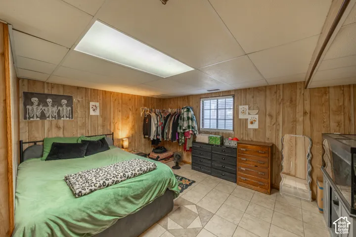 Wood-finish paneled walls, tile flooring, and a drop ceiling with integrated lighting