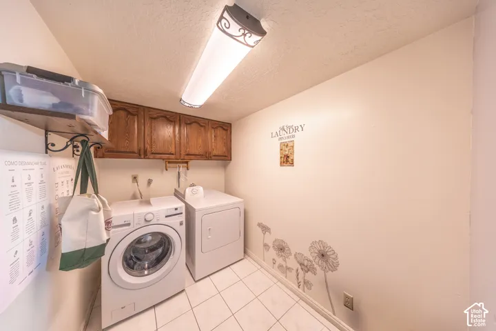 Dedicated laundry area featuring overhead wood cabinetry, a wall-mounted shelf, and tiled flooring