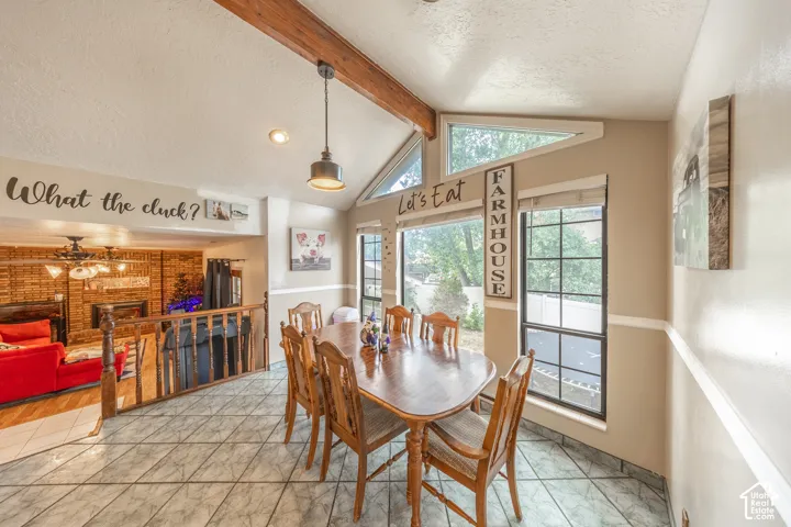 Dining space featuring a wood-finish vaulted ceiling beam, ceramic tile flooring, and large picture windows
