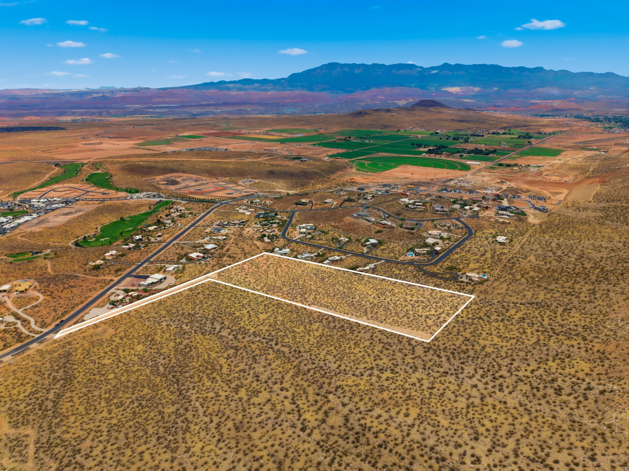 Expansive desert land parcel outlined in white, featuring sparse vegetation and a clear blue sky