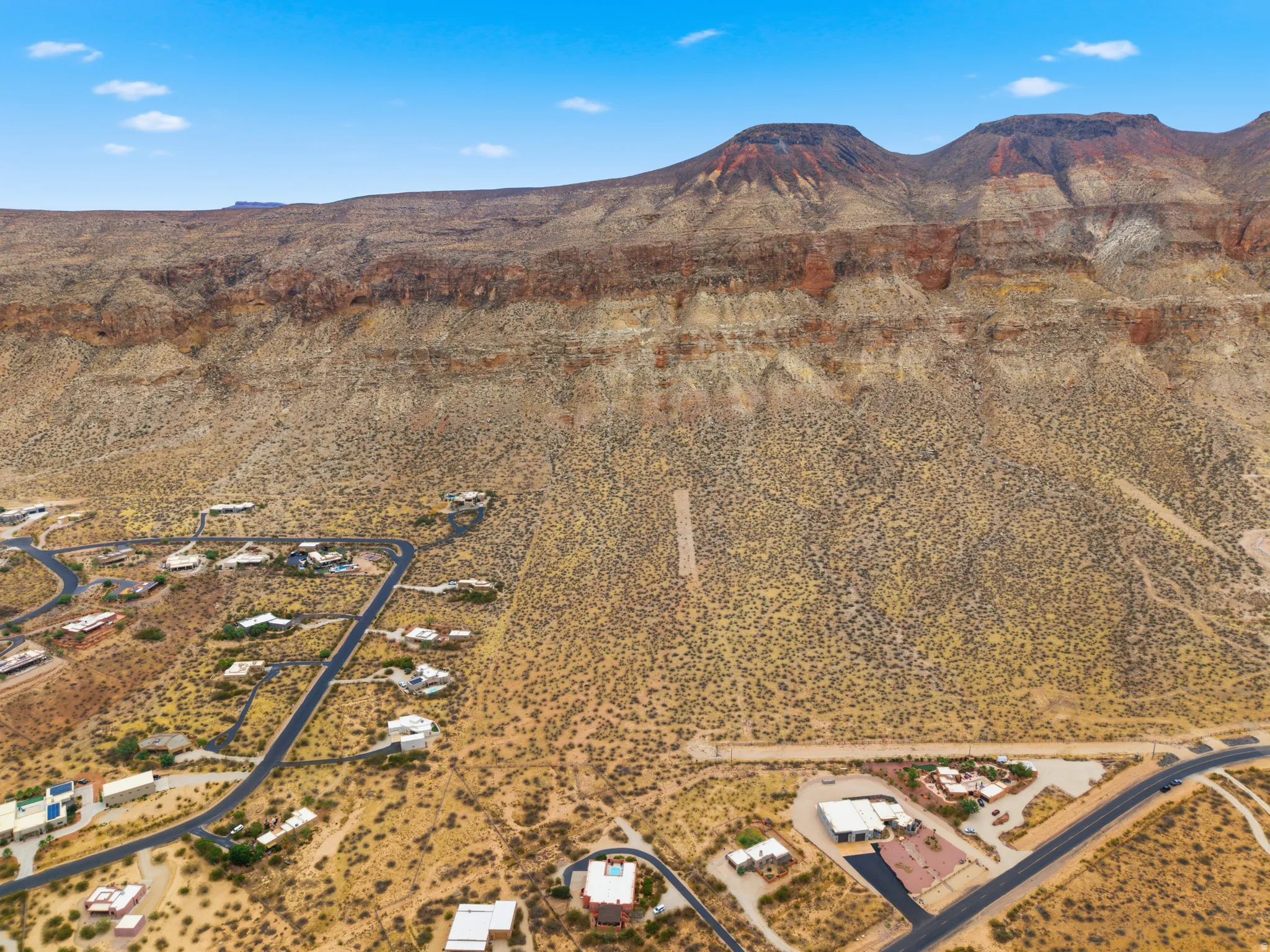 Expansive desert landscape with multiple residences nestled along winding paved roads