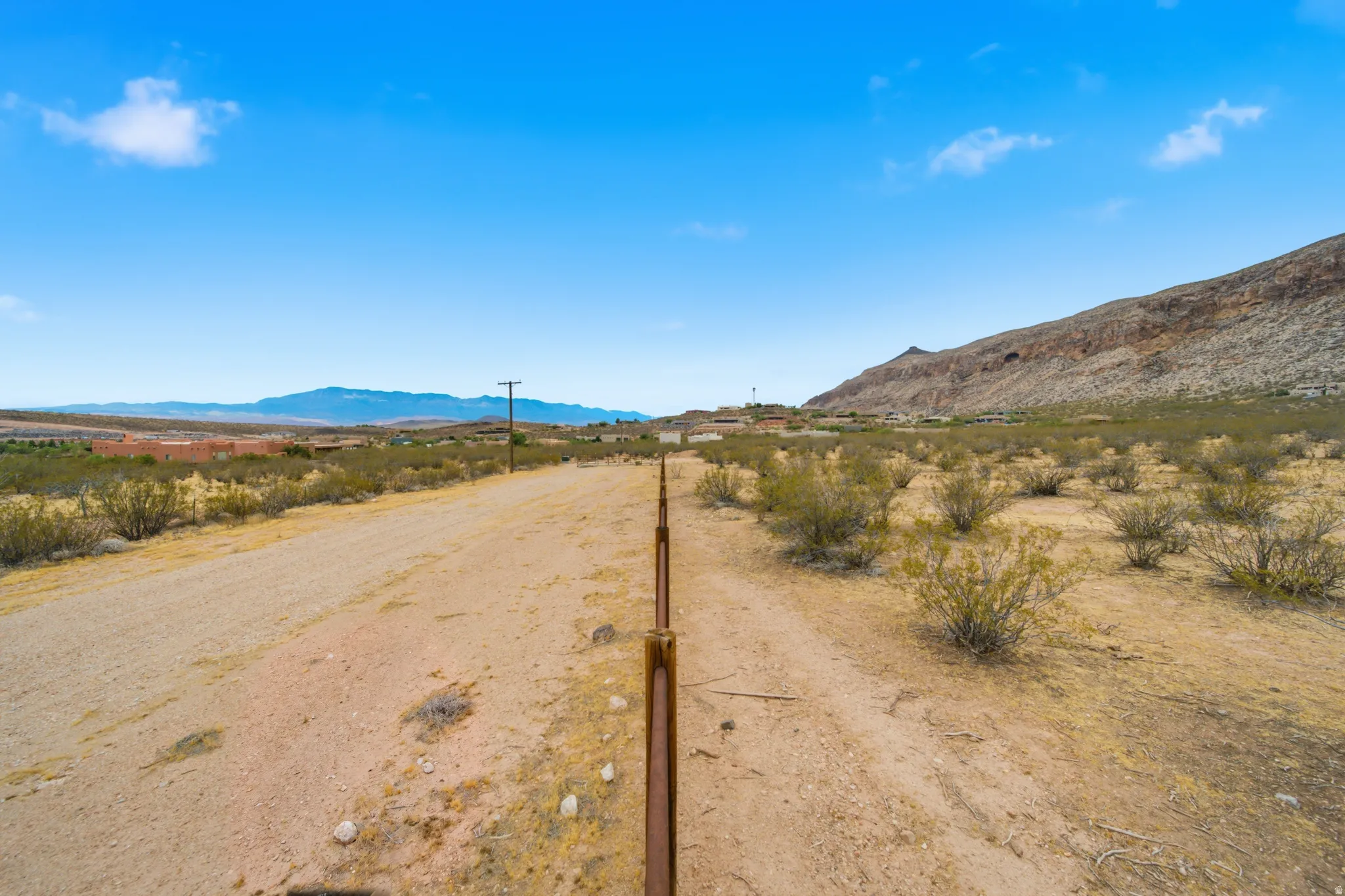Expansive desert landscape featuring a dirt road and scattered brush