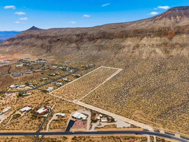 Expansive desert land parcel featuring delineated boundaries, natural arid vegetation, and direct road frontage