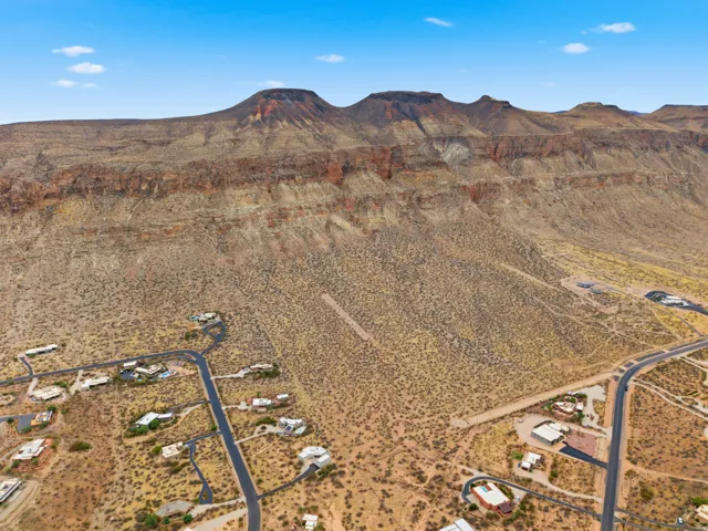 Expansive desert landscape featuring rugged mountain formations, scattered residential properties, paved roads, and natural vegetation