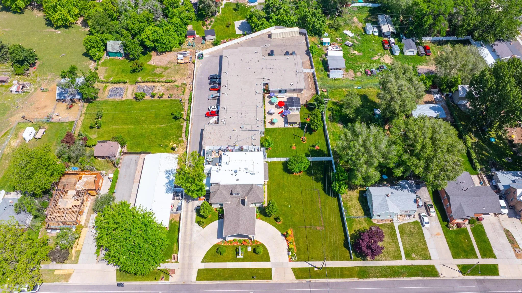 Expansive property featuring a circular driveway, mature landscaping, and a substantial building with a flat roof