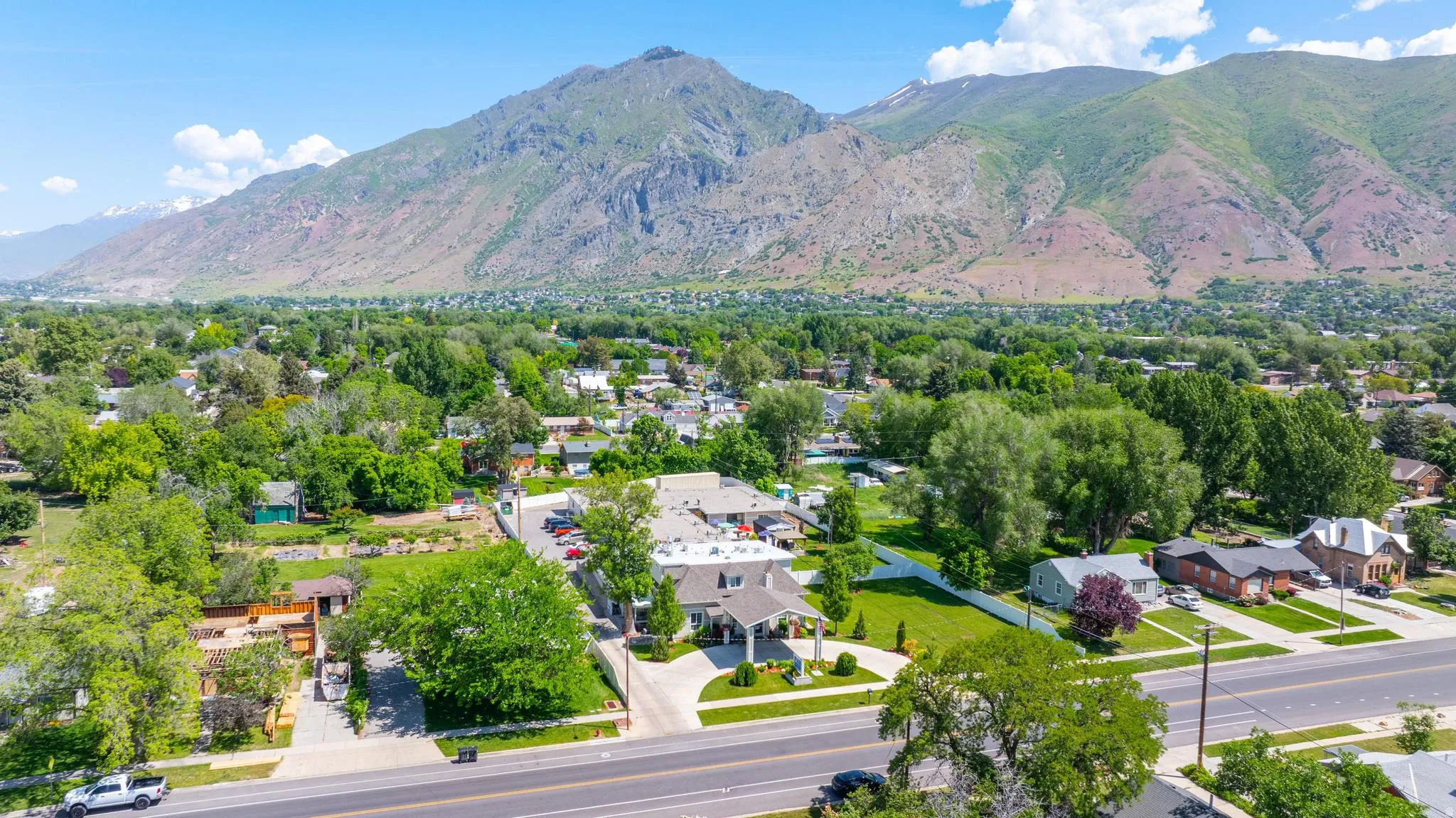 Expansive mountain range backdrop framing a residential area with mature trees and a clear blue sky
