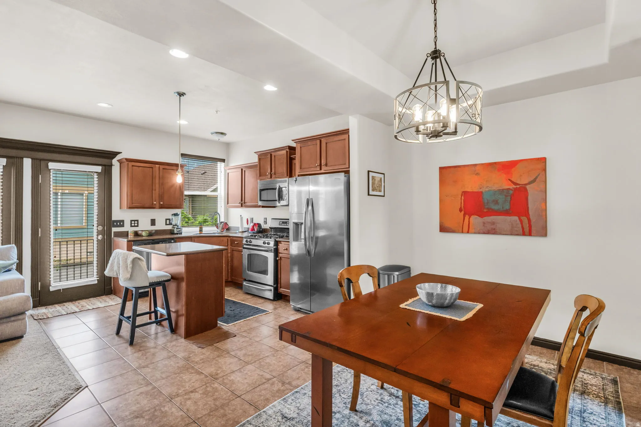 Open-concept kitchen and dining area featuring wood-finish cabinetry, stainless steel appliances, and a central island with countertop seating