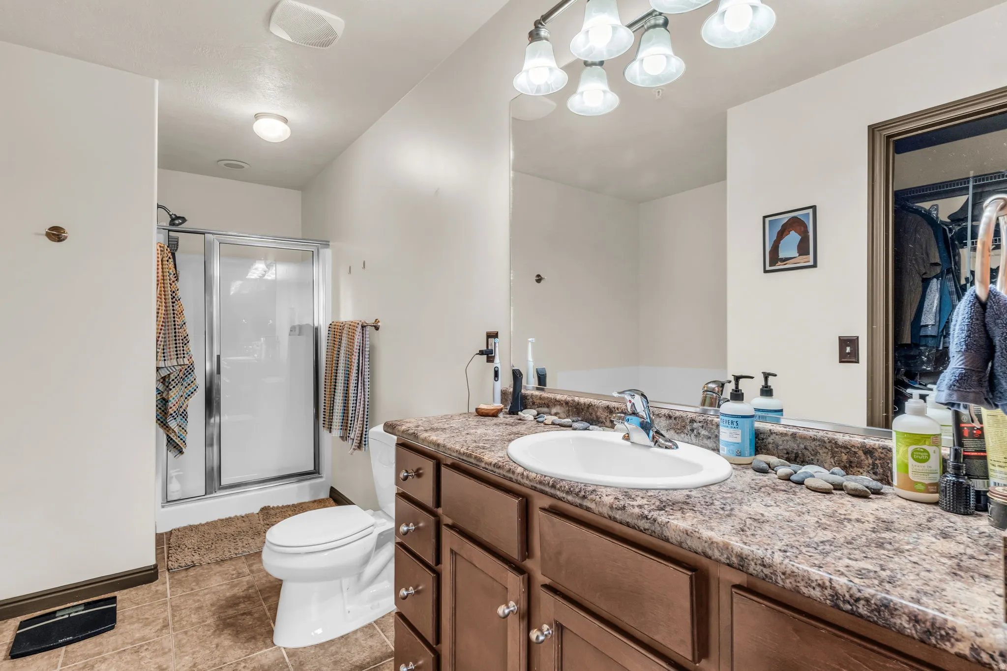 Bathroom featuring a built-in vanity with a stone-finish countertop, an undermount sink, and a chrome faucet