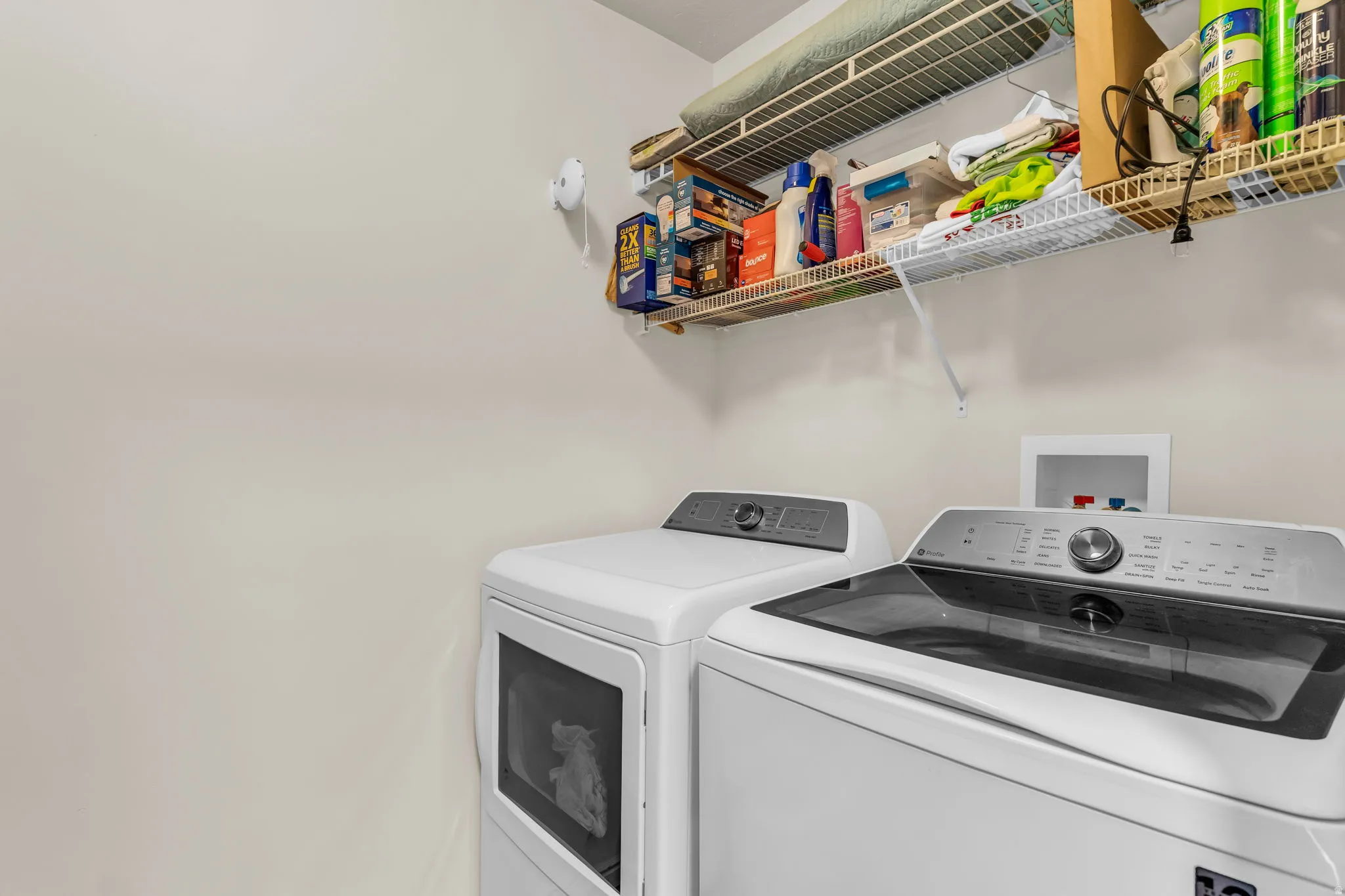 Laundry area featuring neutral wall tones, wire shelving, and utility hookups