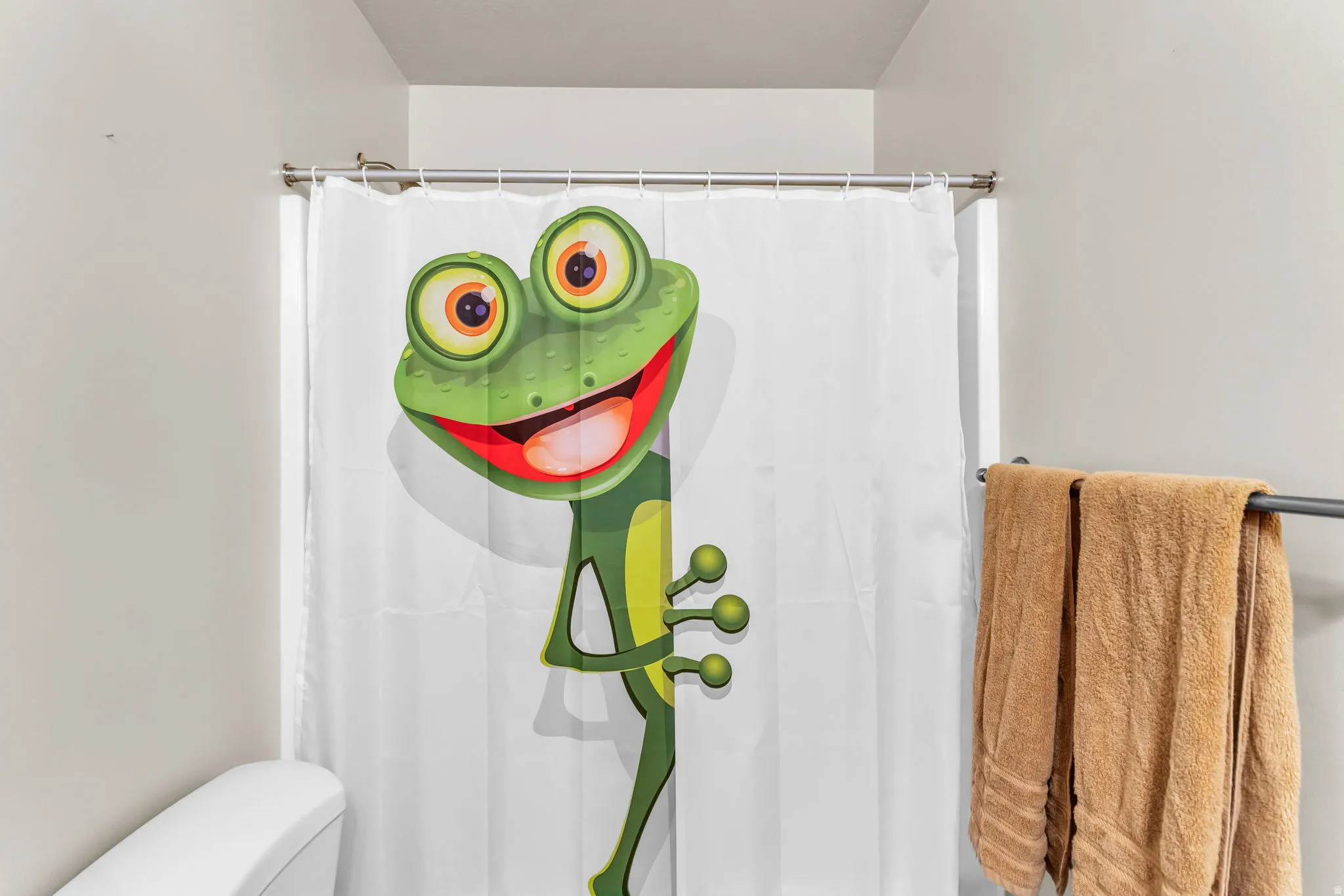 Bathroom featuring a full-sized shower enclosure with a shower rod, a toilet, and a wall-mounted towel bar