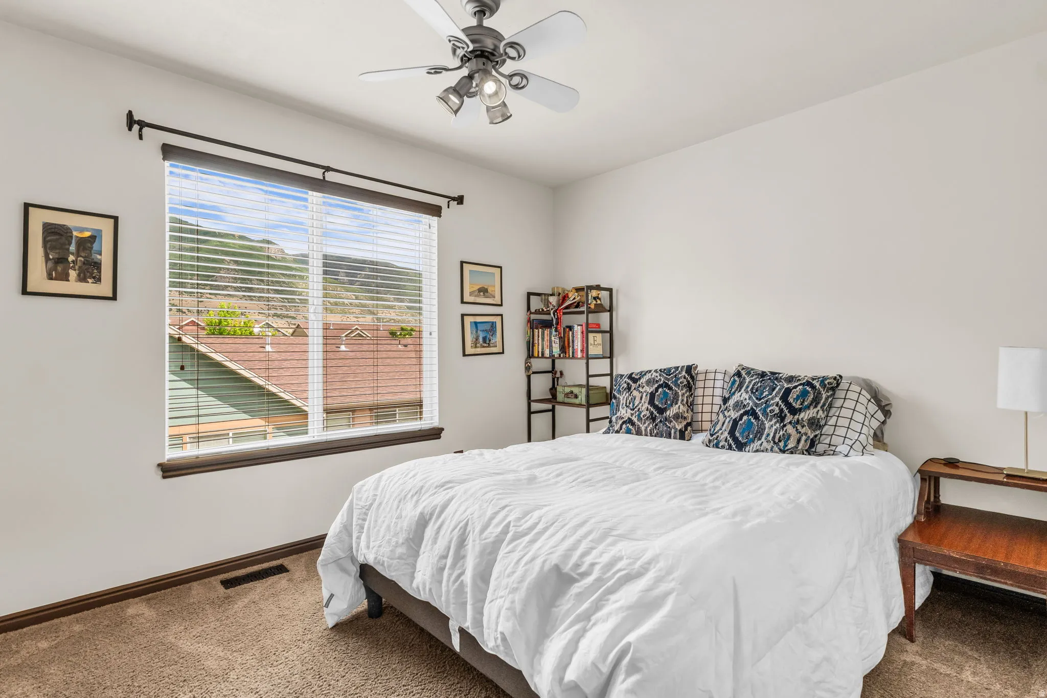 Bedroom featuring a large window with mountain scenery, white walls, and neutral-toned carpet
