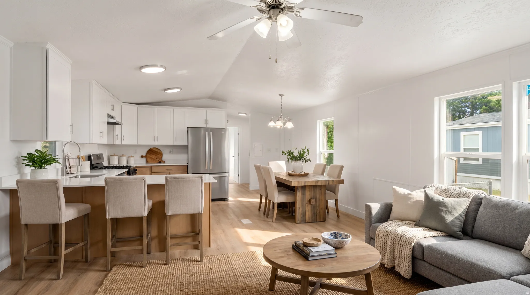 Open-concept living area featuring wood-finish flooring, white walls, and multiple windows