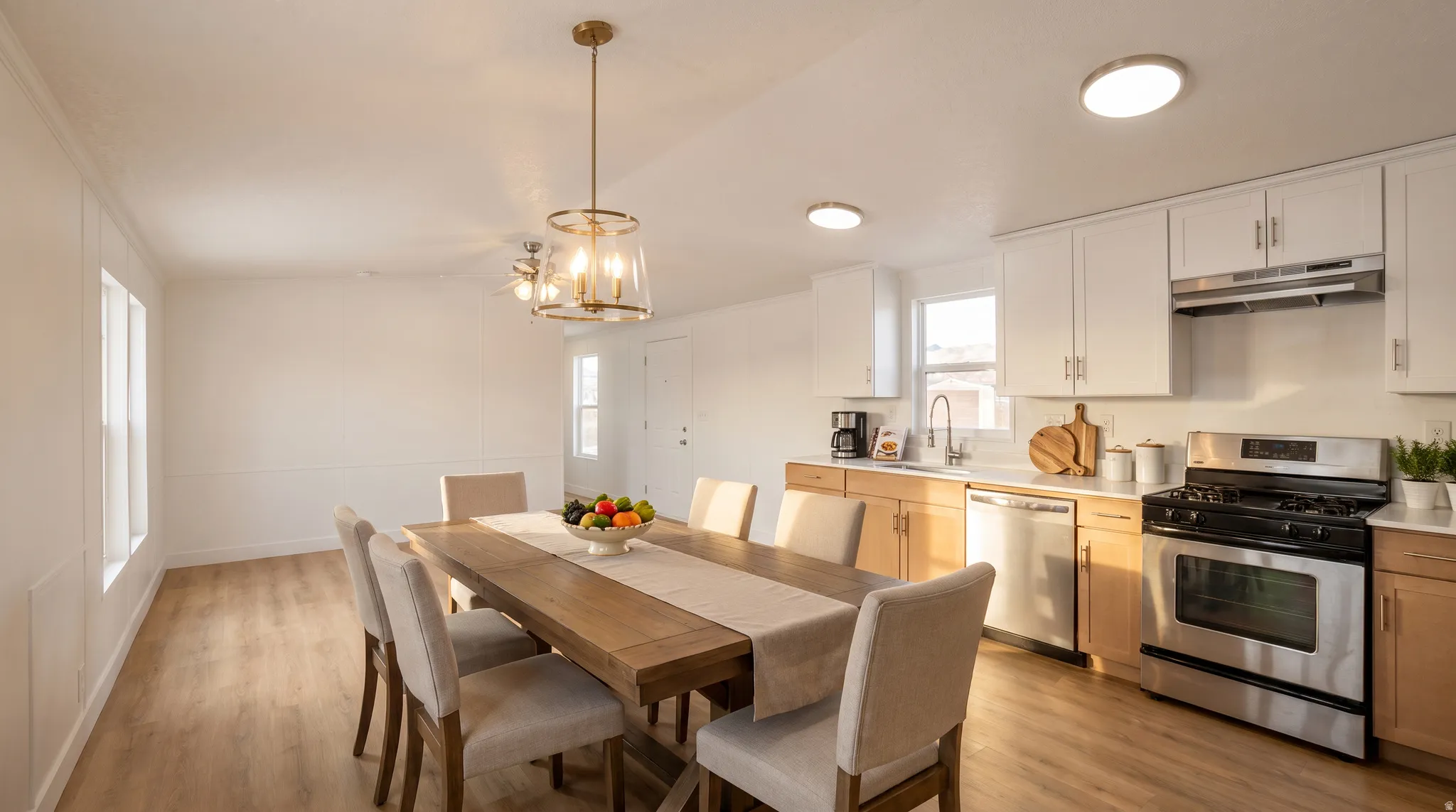 Open concept living space featuring wood-finish flooring, white wall paneling, and a contemporary dining chandelier