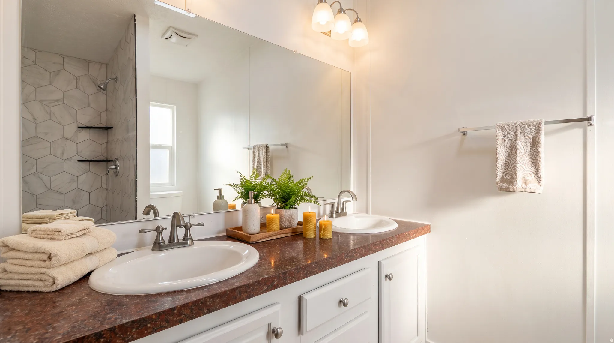 Dual vanity with white cabinetry and dark speckled countertops, featuring two undermount sinks with brushed nickel faucets