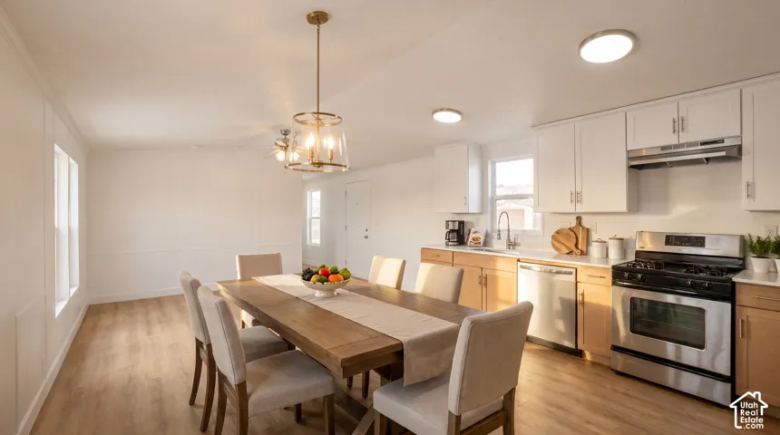 Open concept living space featuring wood-finish flooring, white wall paneling, and a contemporary dining chandelier