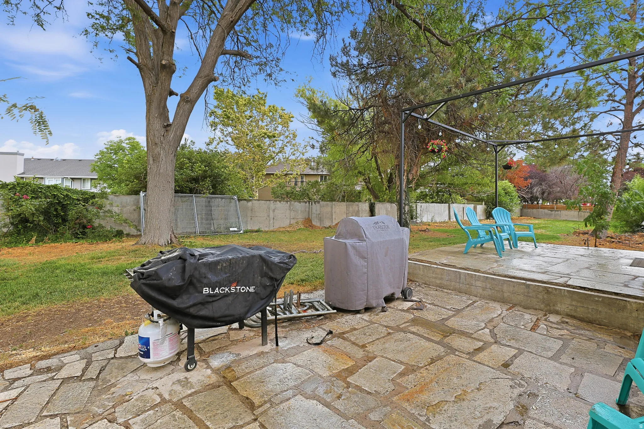 Expansive backyard featuring a natural stone patio and mature trees.