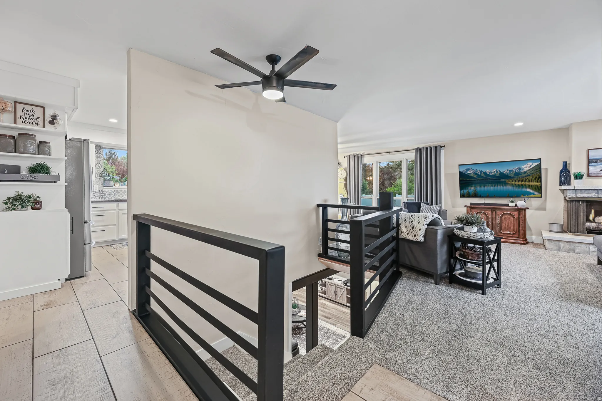 Open-concept living area with new configured staircase featuring custom black railing.
