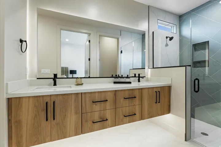 Dual sink vanity featuring wood-finish cabinetry, quartz countertops, and matte black fixtures