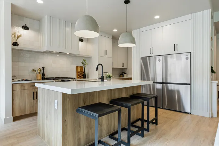 Modern kitchen featuring a large center island with wood-finish paneling and a light-toned countertop