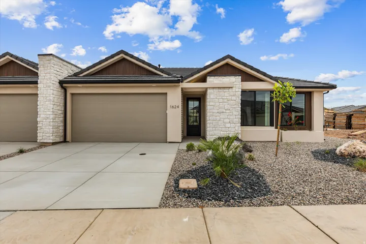 Contemporary facade featuring a stone accent column, dark wood soffits, and a covered entry