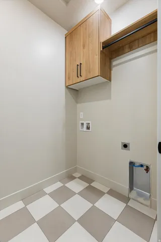 Laundry area featuring checkerboard flooring, light wood-finish cabinetry, and a clothes hanging rod