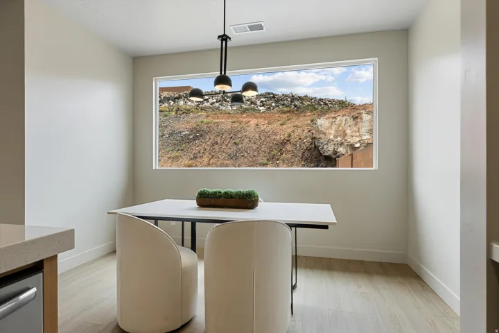 Dining area with a large picture window, a modern multi-bulb pendant light fixture, and wood-finish flooring