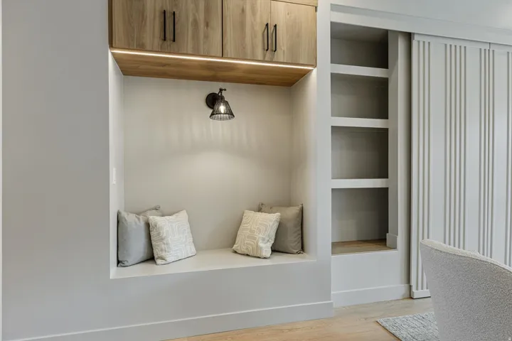 Built-in reading nook with overhead cabinetry and a sconce light