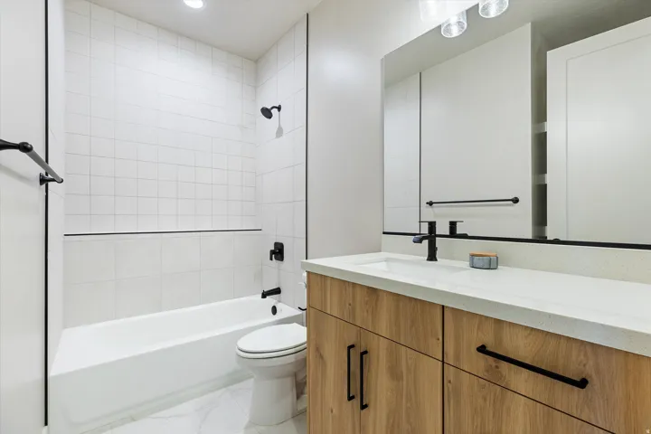 Bathroom with a white bathtub and subway tile surround, featuring matte black fixtures