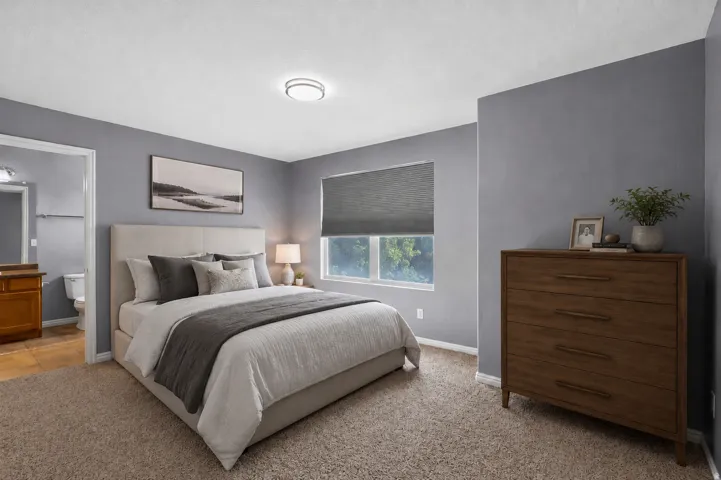 Plush carpeting, a bright window with a roller shade, and a flush-mount ceiling light fixture.  AI staged photo.