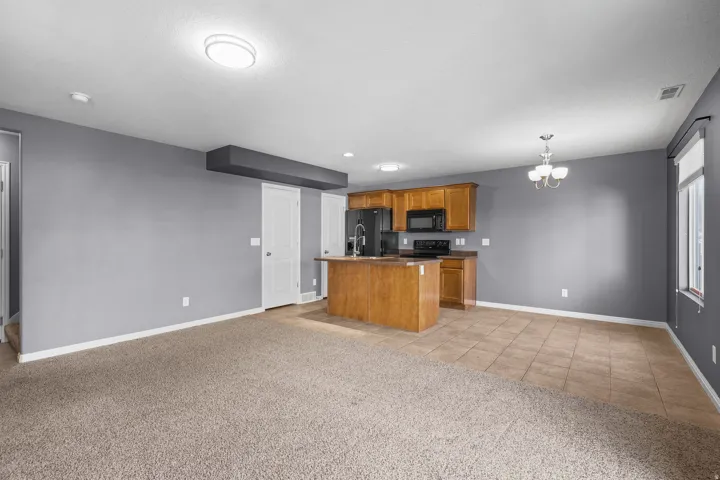 Open-concept living space featuring a kitchen with wood cabinetry, black appliances, and a central island