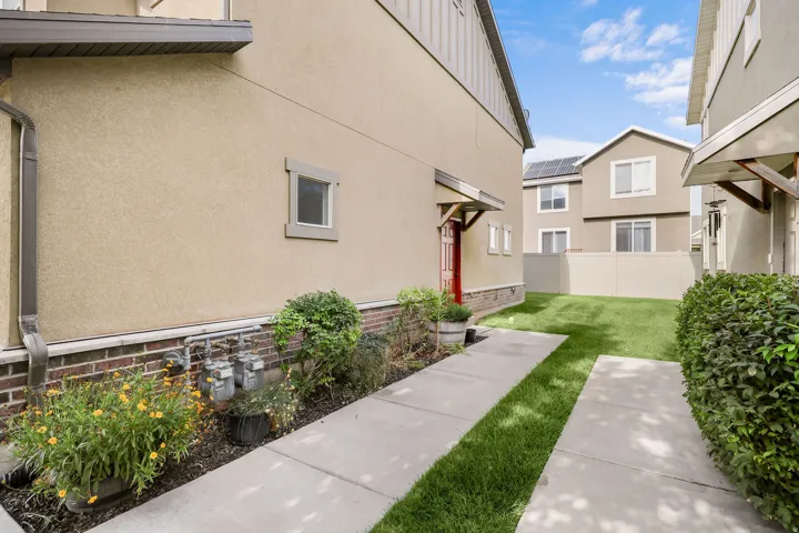 Private outdoor space featuring a manicured lawn, concrete pathway, and established perimeter shrubs
