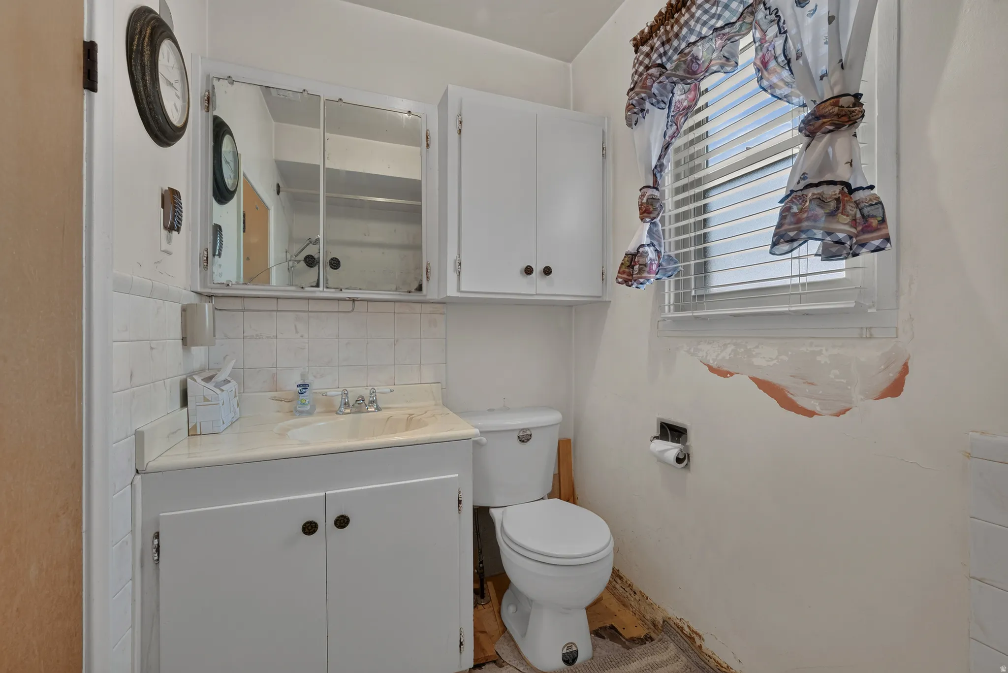 Bathroom featuring a white vanity with a built-in sink, mirrored medicine cabinet, and white wall cabinetry