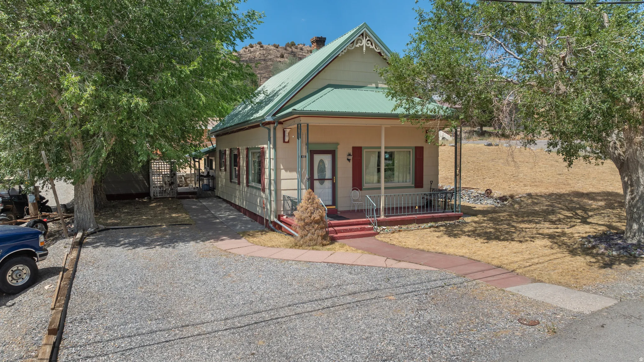 Charming single-story residence with a covered front porch, red-painted steps, and a pea gravel driveway