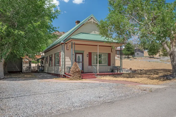Crafted Victorian-style residence featuring a prominent covered front porch, red-painted steps, and decorative gable trim