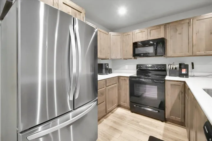 Kitchen featuring stainless steel French door refrigerator, black range, and black microwave