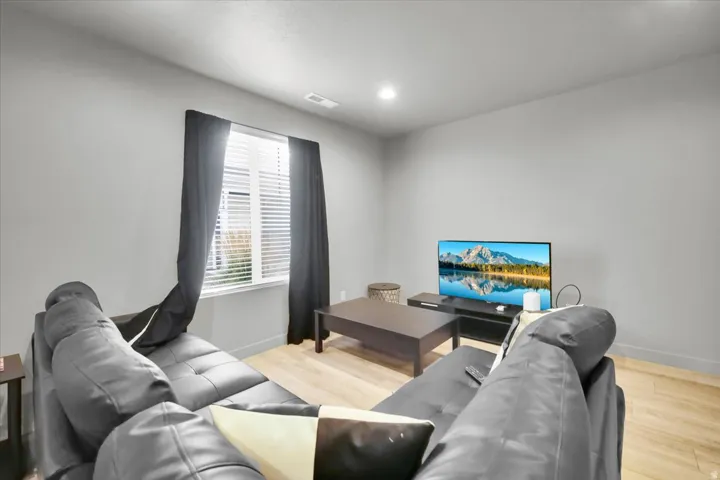 Recessed lighting illuminates this living space featuring light wood-finish flooring and neutral wall tones