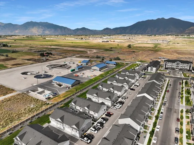 New construction townhomes featuring multi-story designs with attached garages, situated along a paved road with street parking and mature trees