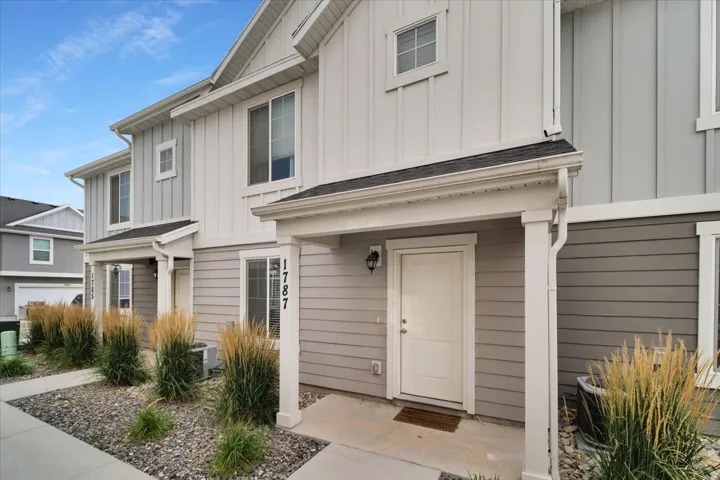 Two-story townhome featuring a covered entry porch and a multi-textured facade with vertical and horizontal siding