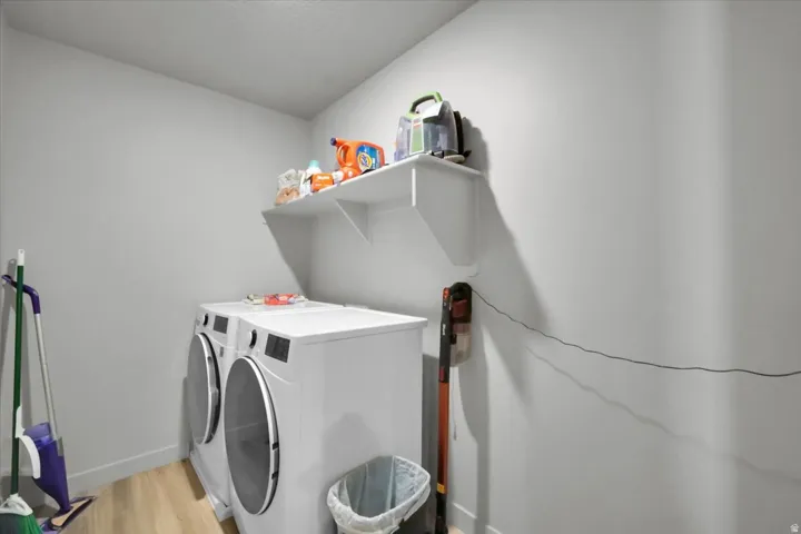 Laundry area featuring wood-finish flooring, white walls, and built-in shelving