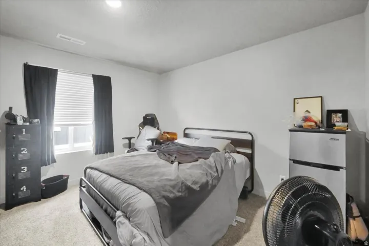 Bedroom featuring light neutral wall paint, a single window with blinds, and carpet flooring