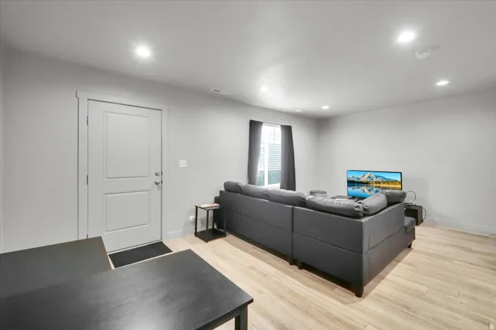 Recessed ceiling lighting illuminates a spacious living area featuring light wood-finish flooring