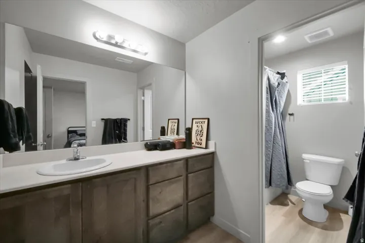 Double vanity with an integrated sink, broad wall mirror, and wood-finish cabinetry