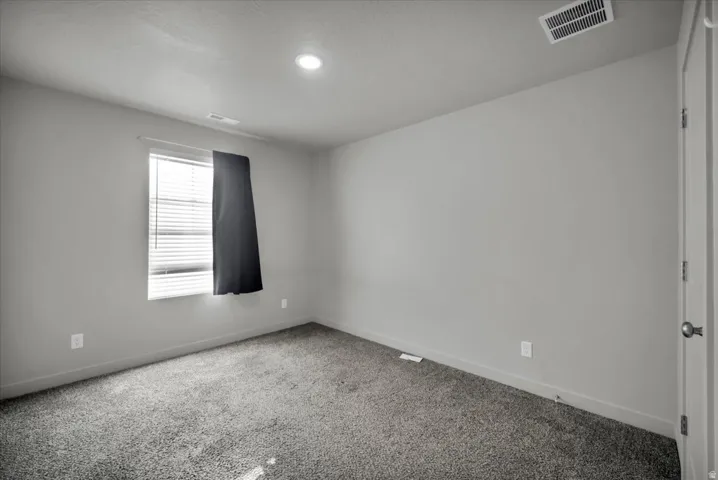 Neutral tone wall paint with a window featuring blinds, complemented by a recessed ceiling light