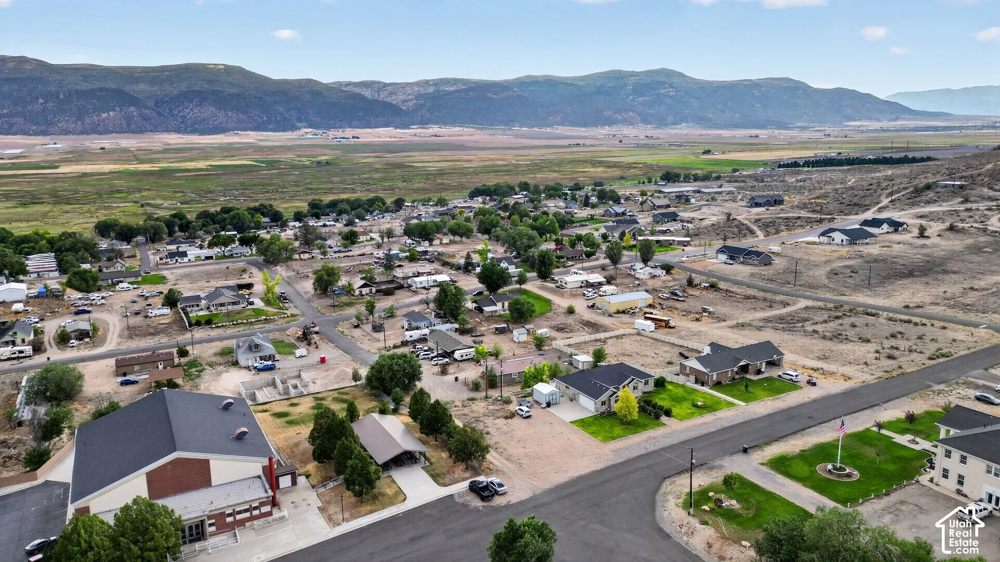 Expansive aerial showcasing a residential area with various single-story homes, surrounded by natural landscapes and distant mountains