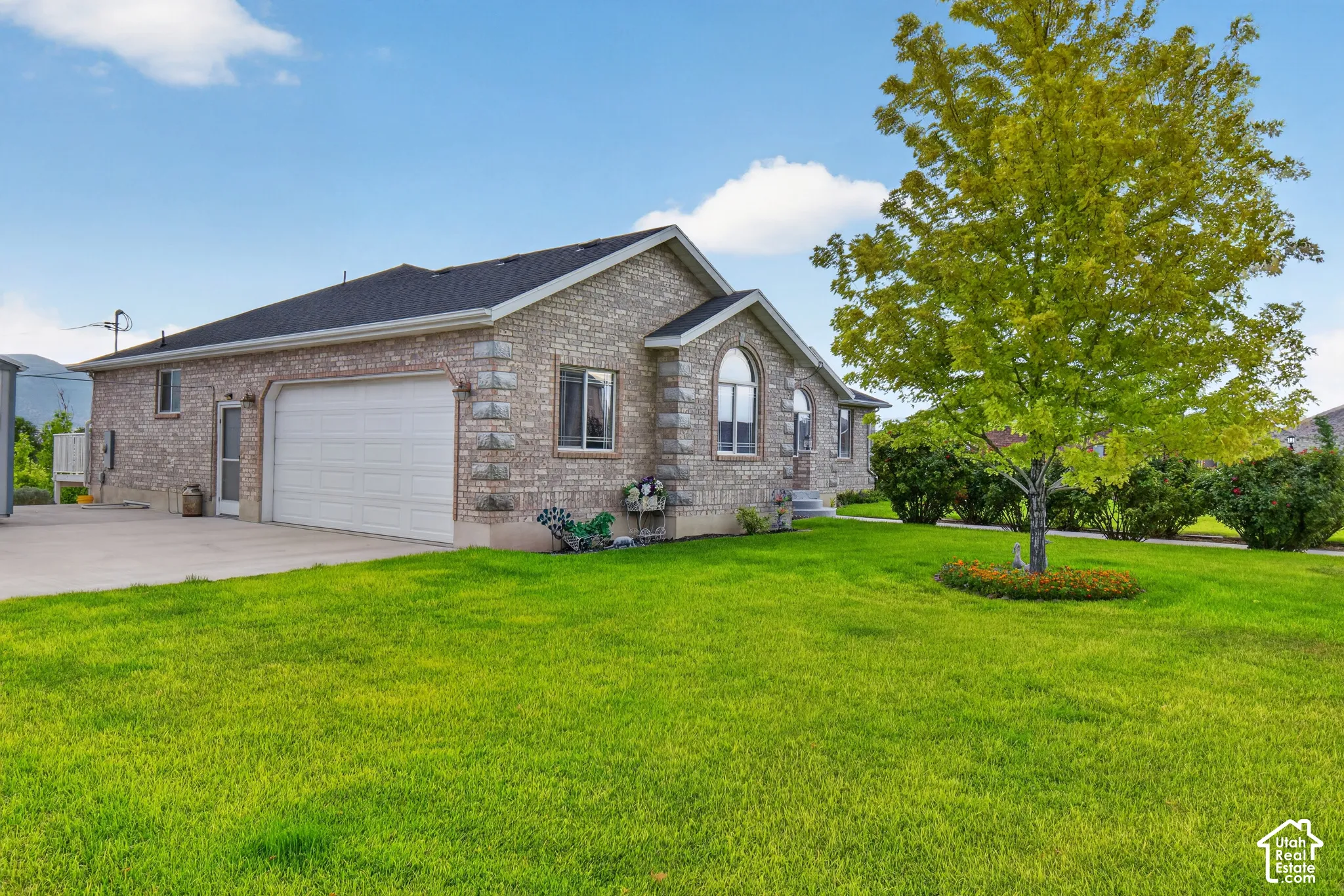 Stone veneer exterior with a dark shingle roof and an attached garage